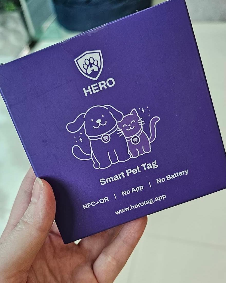 A hand holding the purple Hero box, printed with Smart Pet Tag, NFC + QR, No App, No Battery